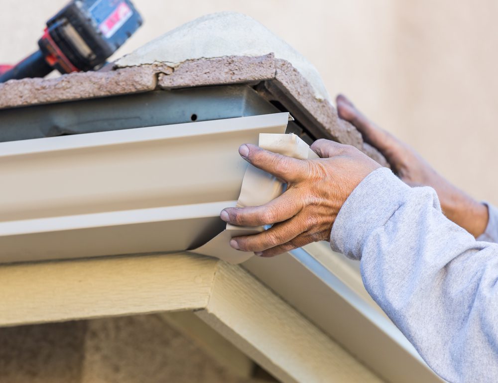 Worker,Attaching,Aluminum,Rain,Gutter,To,Fascia,Of,House.